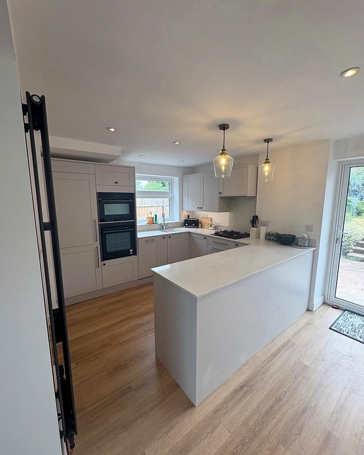 Bright open kitchen with two glass pendant lights over a peninsula and recessed downlights