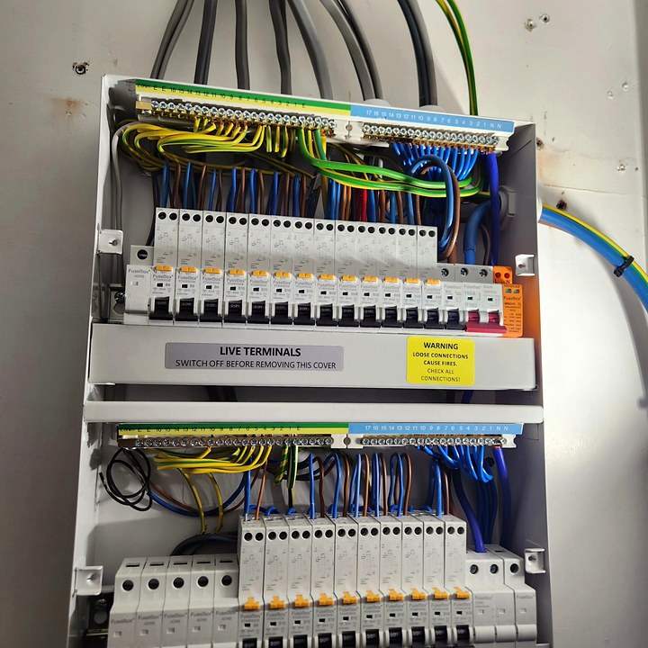 New double-stacked consumer unit with the cover off, showing neatly dressed wiring and rows of RCBOs