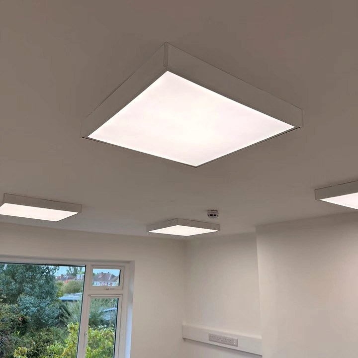 Square surface-mounted LED panel lights on the ceiling of a bright office